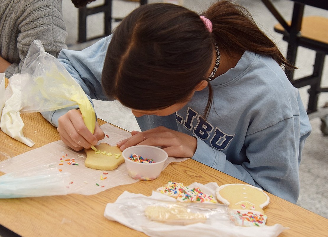 Some students, such as Shyla Schroeder, take their time to make their cookies look as refined as possible. The fifth-grader carefully writes out the word “love” on a cookie, so she can add it to her pile of other elegantly decorated treats.