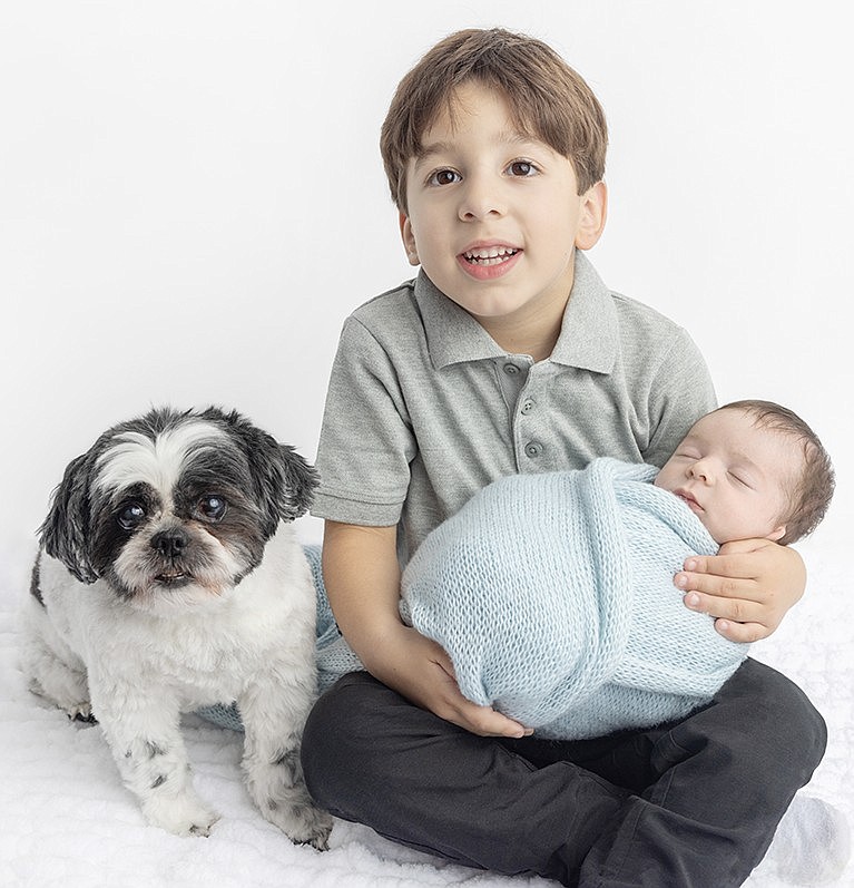 Daniel Melfa holds his new baby brother Johnny while Shadow sits by their side.