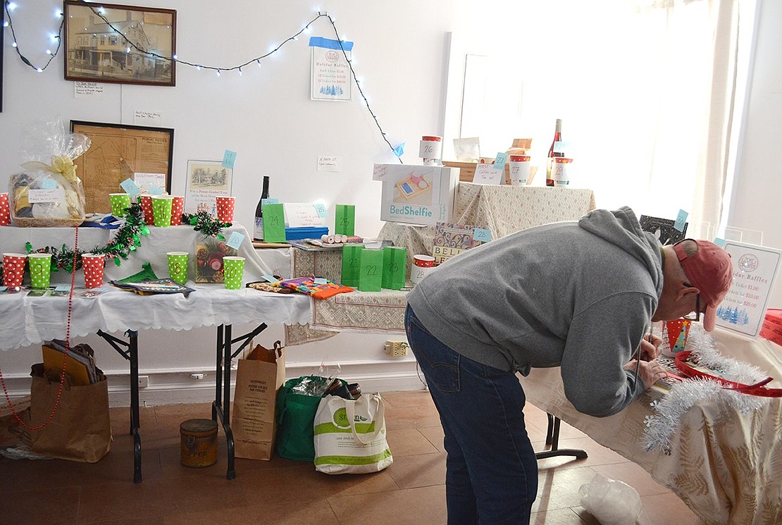 Peter Burke of Fairhaven Lane fills out raffle tickets with his name and telephone number to drop into the cups corresponding to items he is interested in winning.