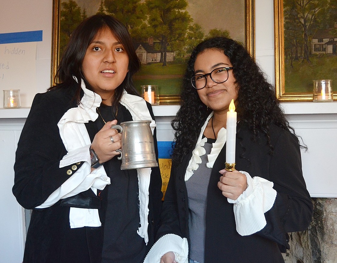 Port Chester High School juniors Gissel Loja and Sophia Tellez, dressed up in colonial garb available at the Winterfest celebration, toast to the holiday season.