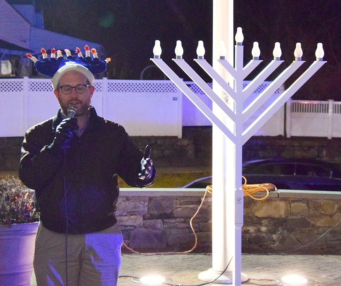 Donning his festive menorah hat, Congregation KTI Rabbi Ben Goldberg says a few words before leading the Chanukkah blessings and lighting the menorah to kick off the gelt drop on the last night of the Festival of Lights.