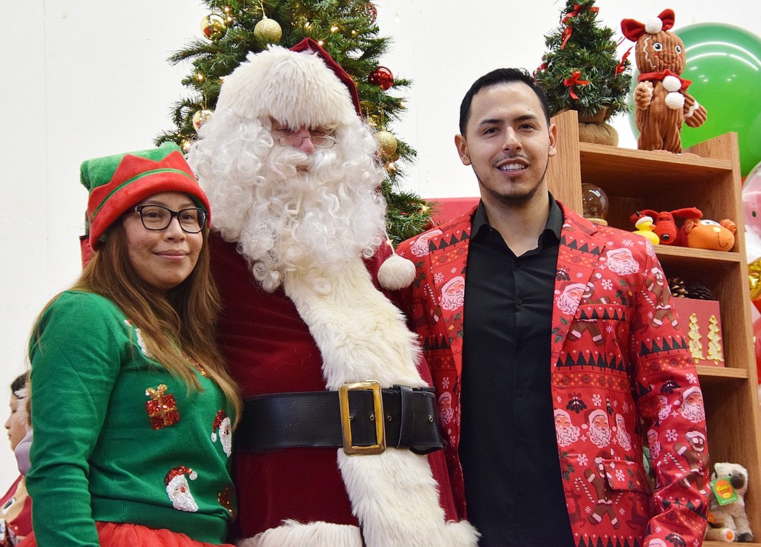 Santa Claus, portrayed by John Mecca, poses with an elf who also serves as Deputy Rye Town Clerk Stephanie Maciel and Don Bosco Community Center Program Director Andres Alvarez on Saturday, Dec. 16. They’re preparing for the second session of the “Breakfast with Santa” at the center, an annual event where families are welcomed to have a meal and receive one of the many gifts that have been donated by local organizations.