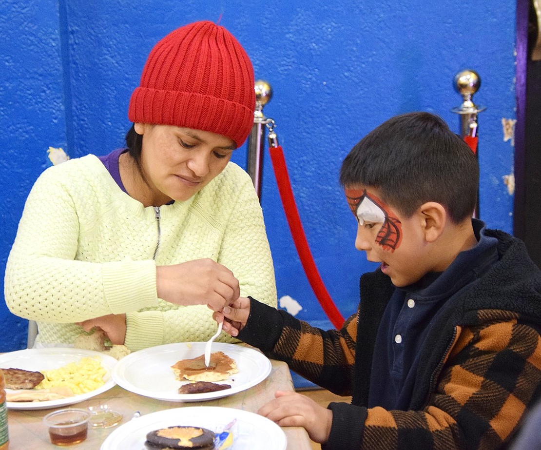 With the Spider-Man face paint still wet, Port Chester 6-year-old John Suquilonda gets help from his mom, Maria, with his pancake.