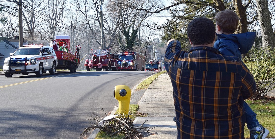 Port Chester resident David Sharpe points out Santa to his 3-year-old son James as the Port Chester Fire Department Santa Run passes by on Saturday, Dec. 16. They’re also keeping an eye out for James’ grandfather Bart Didden, a Port Chester trustee who drove an engine in the procession, as they stand near the Didden home on Betsy Brown Road.