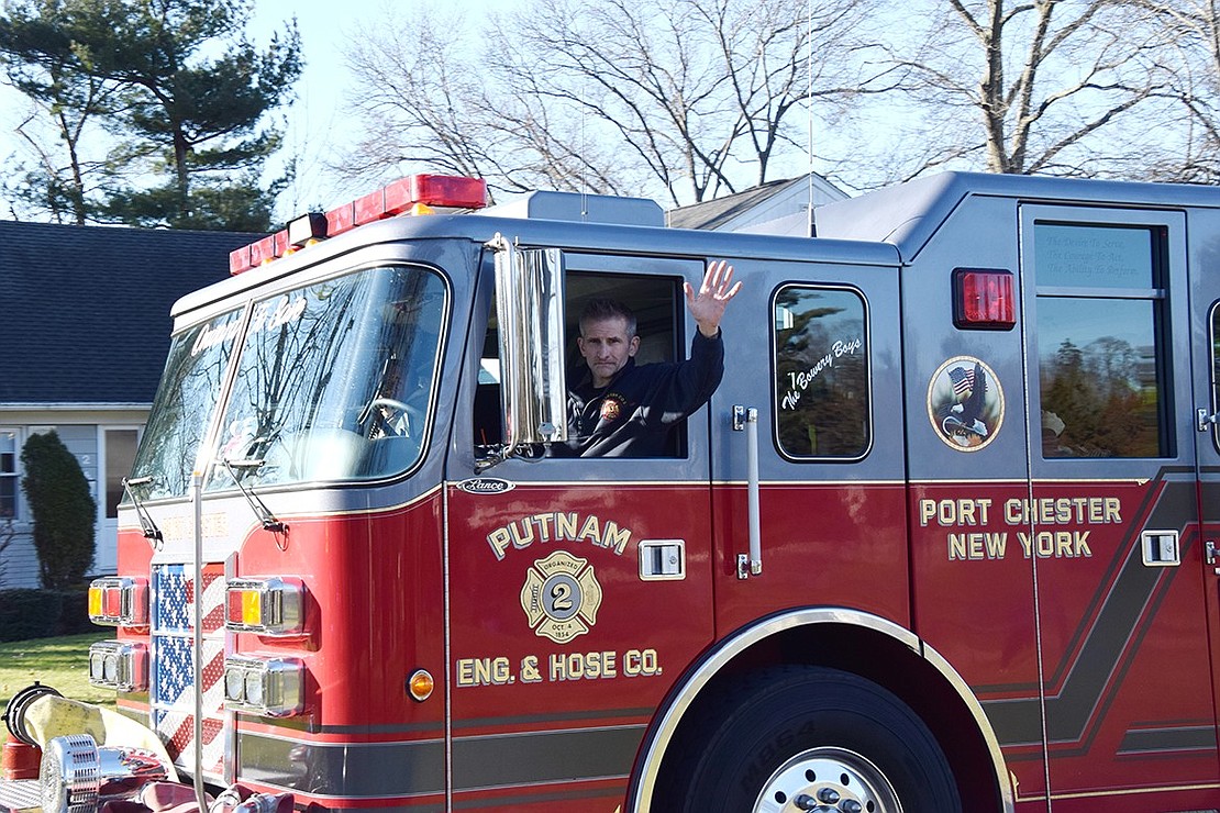 Port Chester firefighter Frank Cervinka waves while he drives a Putnam Engine & Hose Co. truck through Rye Brook.