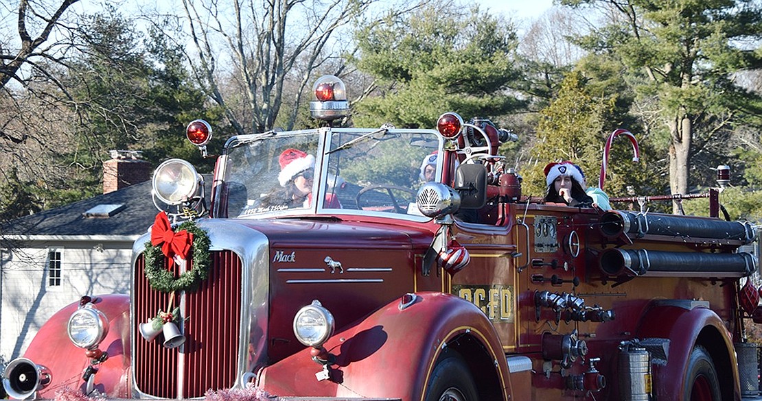 Fire Chief Angelo Sposta drives his personal antique fire engine in the caravan with his wife, Katelyn, in the passenger seat along with their son William. Gianna Carpentieri goes along for the ride in the rear of the vintage truck.