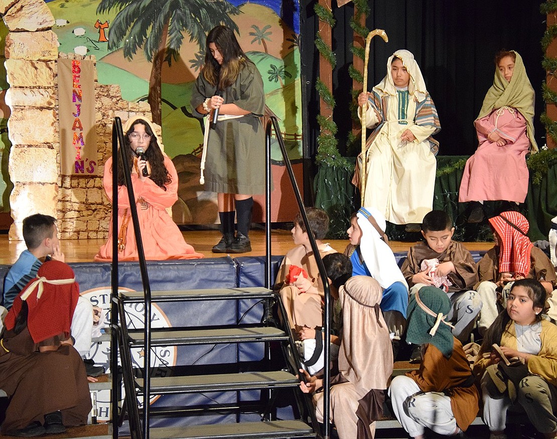 Rachel the innkeeper’s wife (played by Angel Espada) crouches and sings to the inn’s servant (played by Juliette Ianni) of her concern about Joseph and Mary (played by José Abreu and Ana Crespo) who were turned away from the hotel. Other students making up the ensemble sit at the foot of the stage.