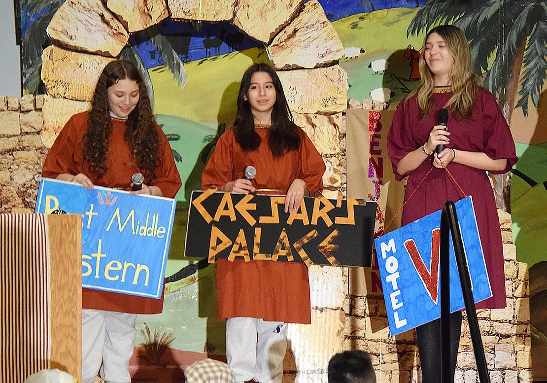 Attempting to rebrand the inn to make it more attractive to travelers, hotel staffers played by Alanah Campos (left), Luciana De Avila and Gianna Marriott present humorous new name ideas—“Best Middle Eastern,” “Caesar’s Palace,” and “Motel VI.”