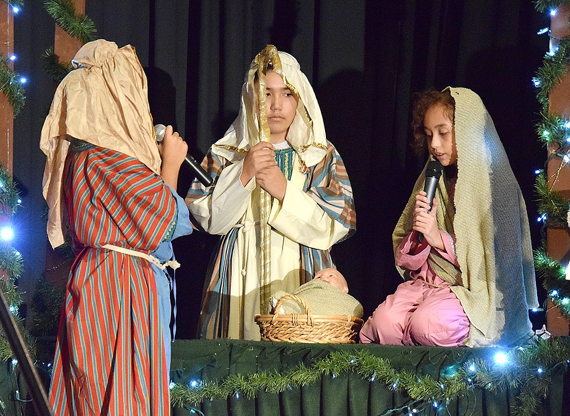 Now understanding the miracle of Jesus’s birth and rectifying his mistake of turning the pregnant family away, the innkeeper Benjamin (left, played by Matthew Valdovinos) invites Joseph and Mary (played by José Abreu and Ana Crespo) inside. The Corpus Christi-Holy Rosary School students are rehearsing for their Christmas show, “Miracle on Bethlehem Street,” on Tuesday, Dec. 19, preparing for their performance the following day.