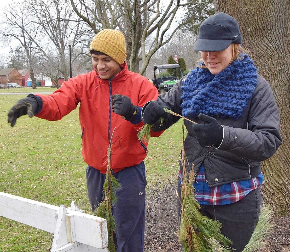 Sustainability Committee Co-Chair Brandon Hermoza-Ricci and member Kikki Short work in the cold to remove plastic cables from some garland. The plastic had to be taken off to run the wreath through the woodchipper.