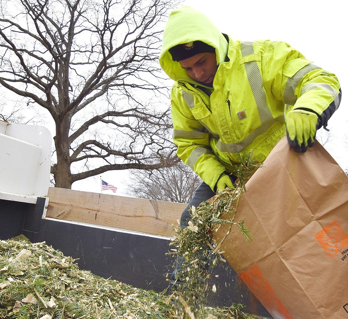 Department of Public Works employee Kevin Aguilar collects mulch into a bag for an attendee to take home. Residents brought reusable shopping bags, garbage bags, yard waste bags and buckets to collect the gardening materials.