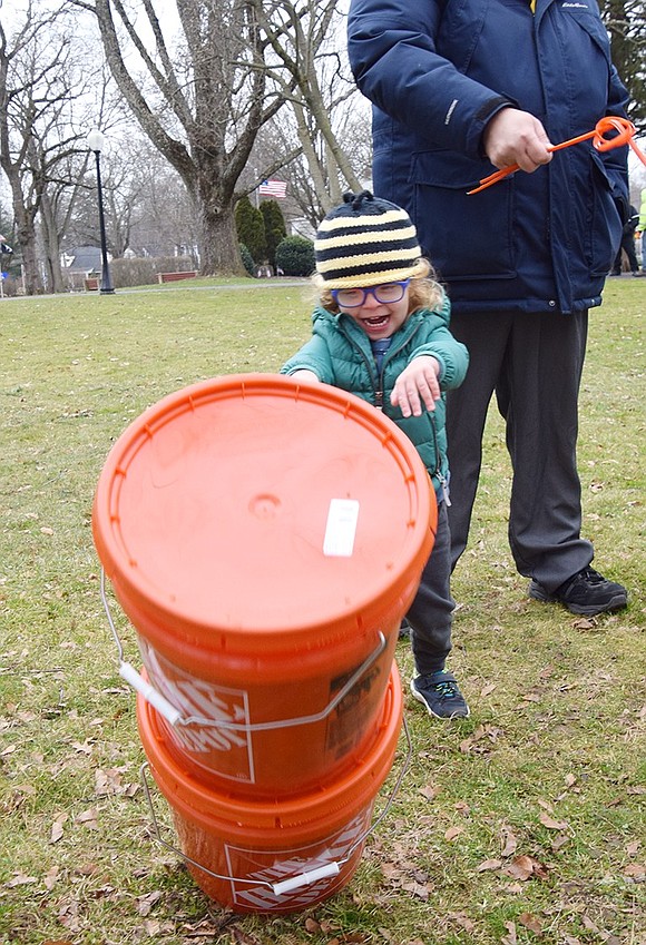 Three-year-old Nate Butkiewicz of Locust Avenue tips over his family’s buckets of wood chips after their tree was shredded.