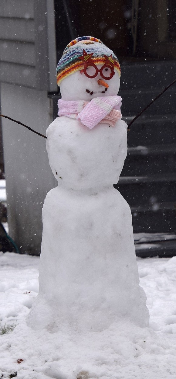 A trim snow figure with red glasses and a pink scarf stands at 74 Tamarack Rd.