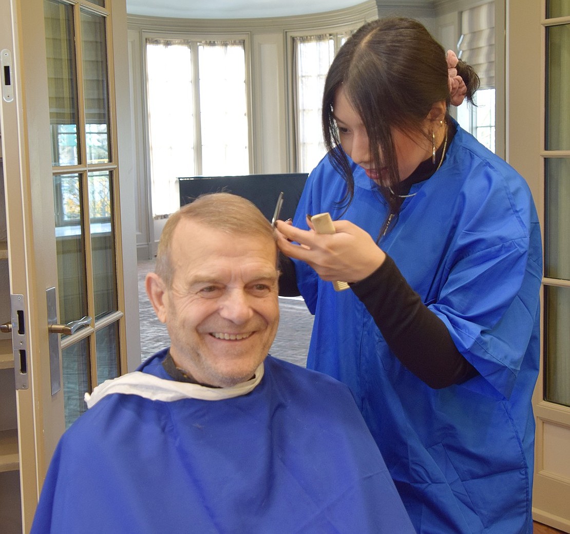 White Plains resident Eli De Marco breaks out into a smile as fledgling barber Nicole Ariza of Yonkers cuts his hair.