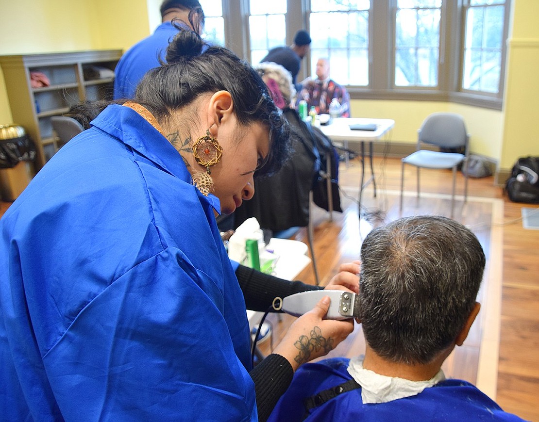 Westchester Barber Academy student Jacquline Flores (left), from the Bronx, uses clippers on Port Chester resident Jorge Cabanillas. Flores said she enjoyed learning the trade.