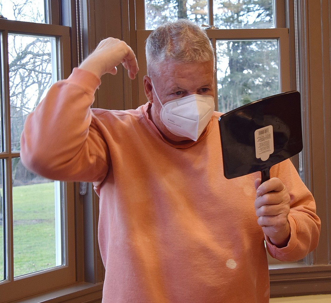 Using a mirror, Port Chester resident Chris Stewart checks to see if his requested mohawk looks good. The 65-year-old said he’s worked a mohawk his whole life, in honor of the “Filthy Thirteen,” a U.S. Army infantry regiment that fought in World War II.