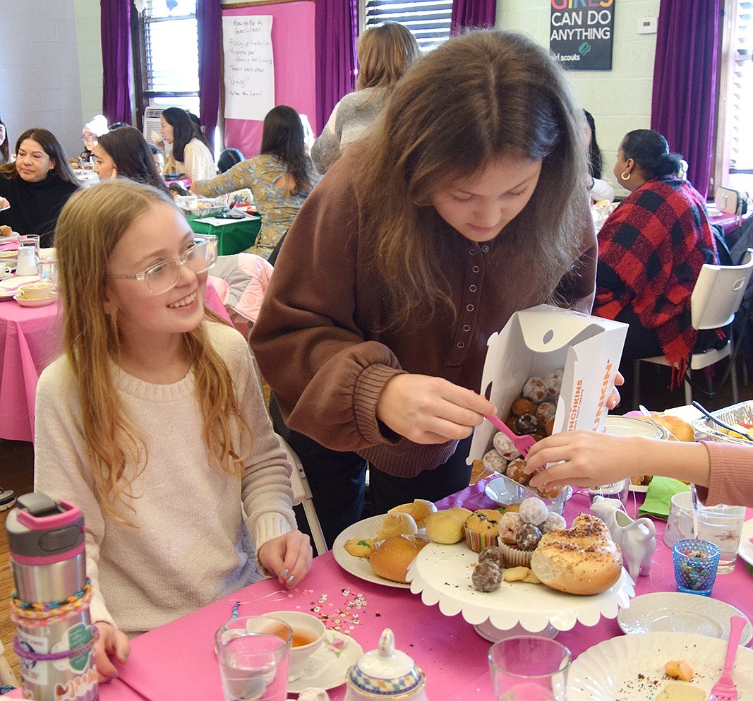 Port Chester resident Cameron Caie (right), 16, serves donut holes to Arianna Butkiewicz, a fifth-grader at King Street School, and her friends.