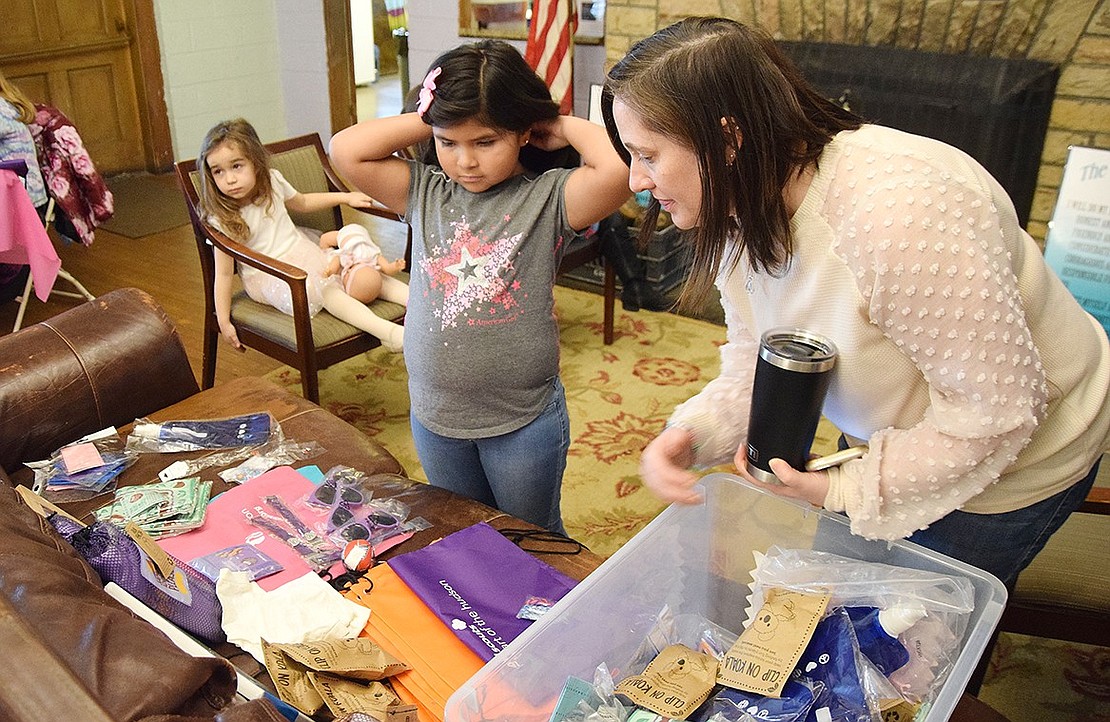 Adelaila Alfaro (left), 7, picks out her prize with Girl Scout Troop Leader Sara Gomez after winning a round of bingo. The Hillcrest Avenue resident chose a painting canvas after a moment of deliberation.