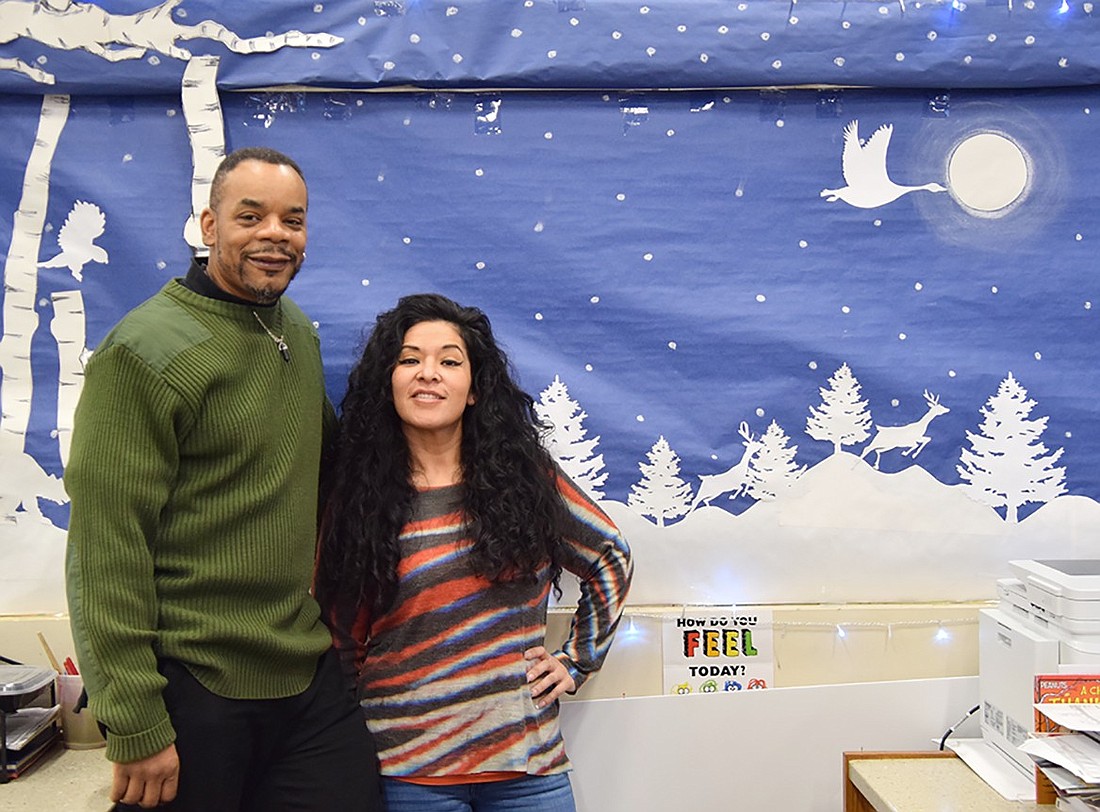 Port Chester-Rye Brook Public Library clerks Mark Parham (left) and Sindy Lopez pose with their latest mural on Wednesday, Jan. 24. The Port Chester natives have been making murals behind the circulation desk for 10 years.