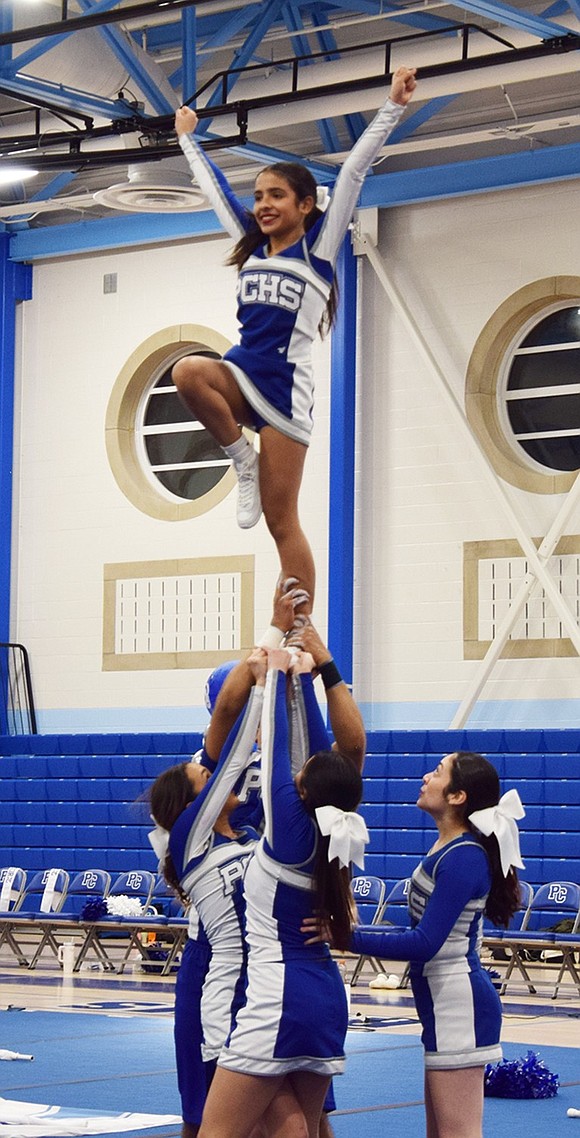 Varsity cheerleader Madison Molina, an eighth-grader, skillfully balances one leg on the hands of her teammates.