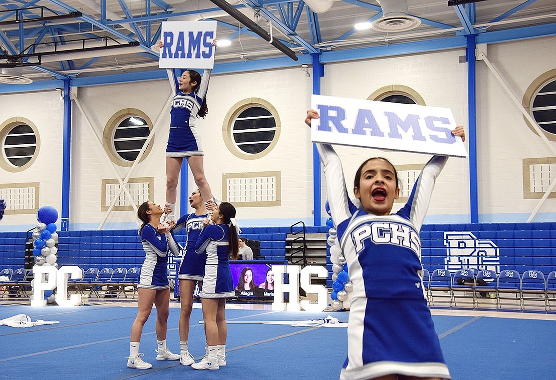Amy Navas (back), a Port Chester High School sophomore, holds a sign showing off her pride for the Rams as she’s held up by other members of the varsity cheer team. From the ground, middle school eighth-grader Madison Molina does the same. The students are performing in the Cheerleading Nationals Send-Off event on Monday, Feb. 6, where the varsity and junior varsity teams were joined by the modified blue and white teams to show the community what they’re capable of ahead of their trip to Disney World in Orlando, Fla. on Feb. 9 for the UCA National High School Cheerleading Championships.
