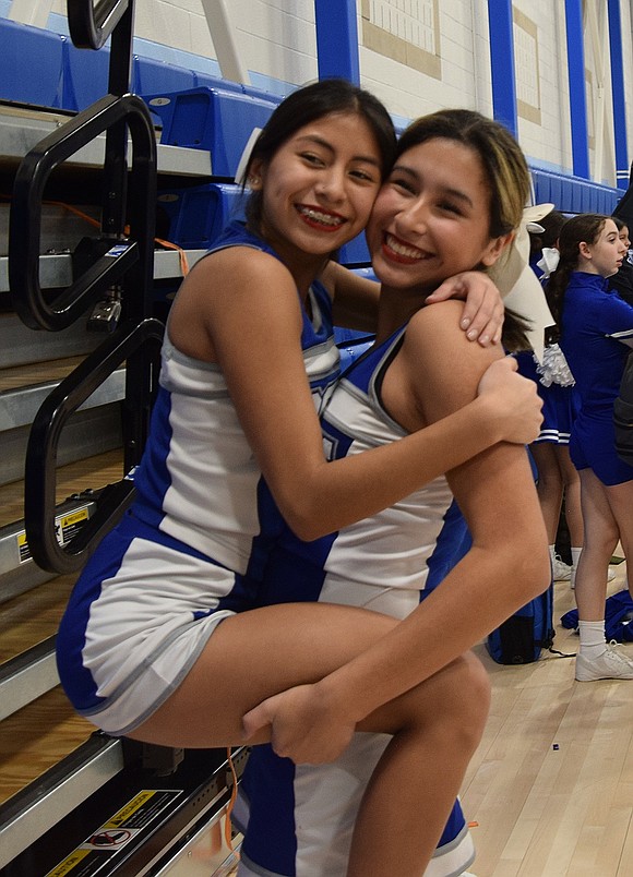 Celebrating her final varsity cheer show, senior Angela Esquival (left) jumps into the arms of sophomore Melina Morban.