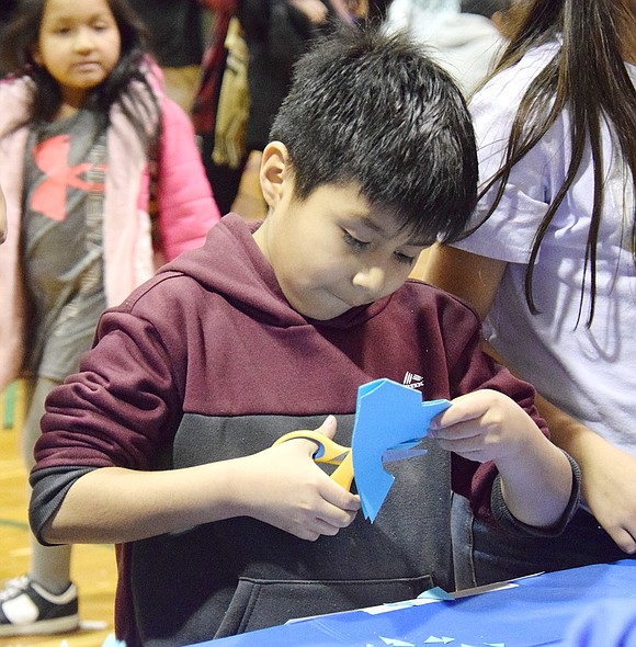 Park Avenue Elementary School fourth-grader Maykel Benalcazar cuts holes and shapes into a piece of blue paper, looking forward to seeing how his snowflake craft will turn out.