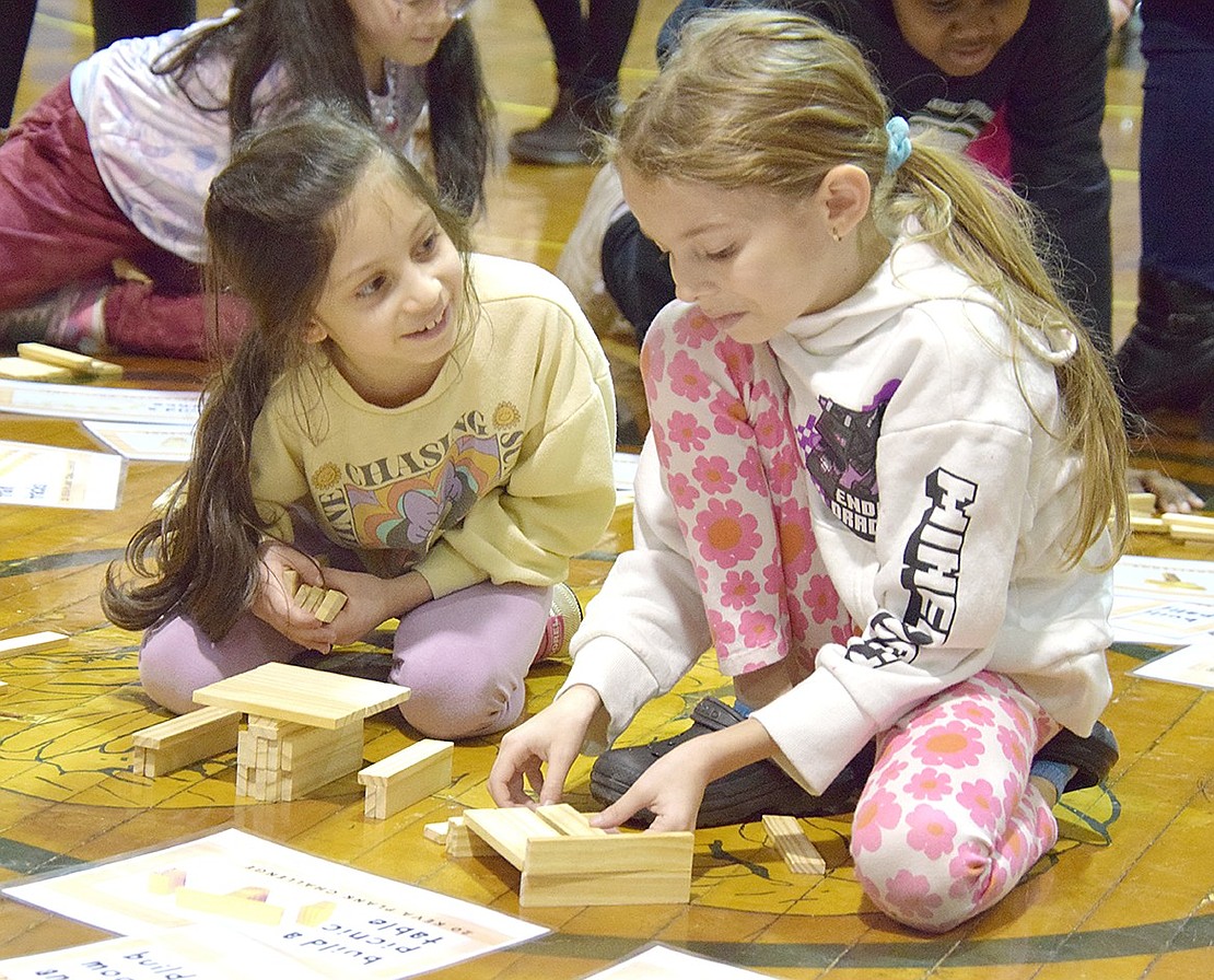 Catching up with some giggles, Park Avenue Elementary School friends third-grader Catalina Saenz-Kaufman (left) and second-grader Kaitlyn Pirrone sit on the floor and work on building blocks together.