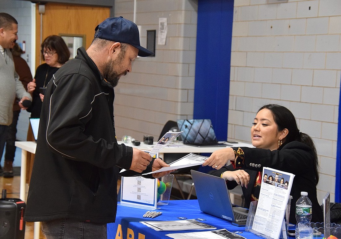 Jesus Gonzalez, a Port Chester resident, accepts a packet of information from New York State Department of Labor Business Services Representative Genesis Retamozo at the Job Fair for an Emerging Economy at the Carver Center on Friday, Feb. 2. The literature will connect him to resources the agency offers.
