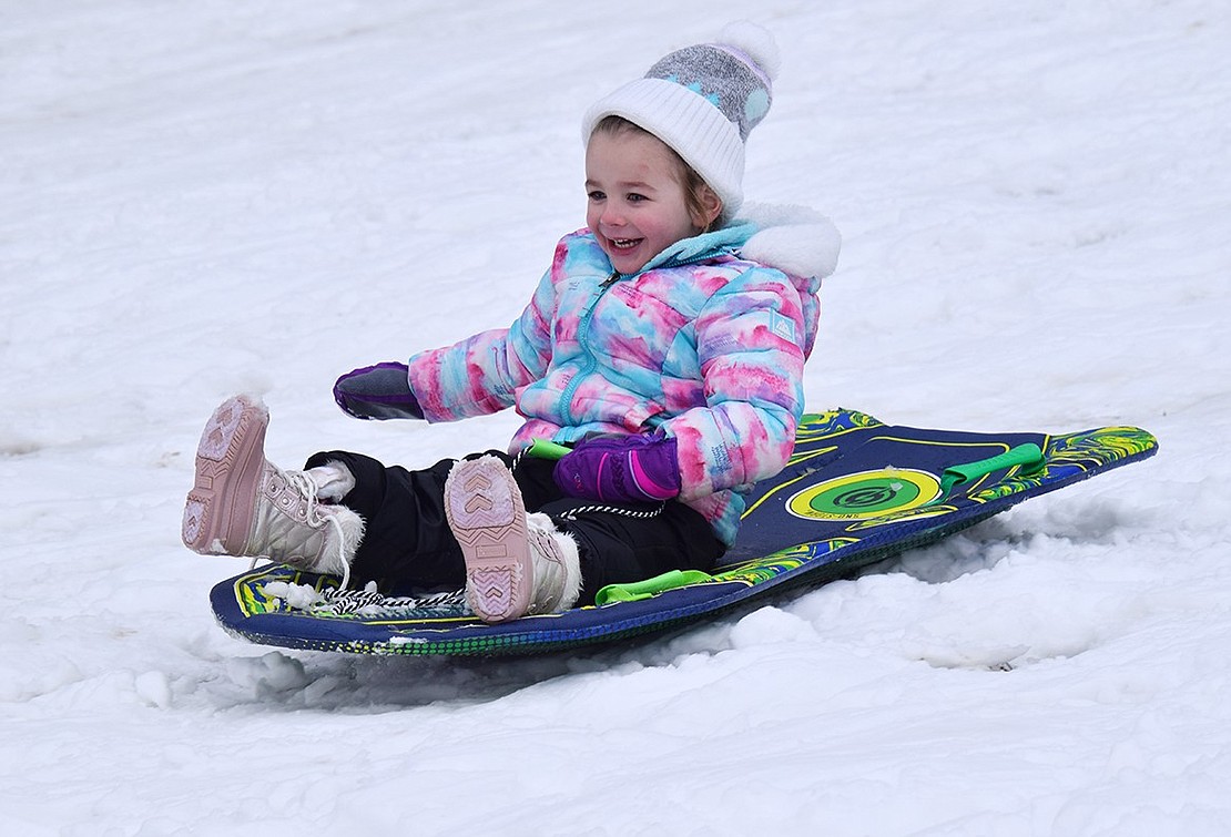 Three-year-old Jordan Jacobson of Tamarack Road, bundled up in colorful garb, is thrilled to slide down one of the more gradual hills at Crawford Park all by herself.