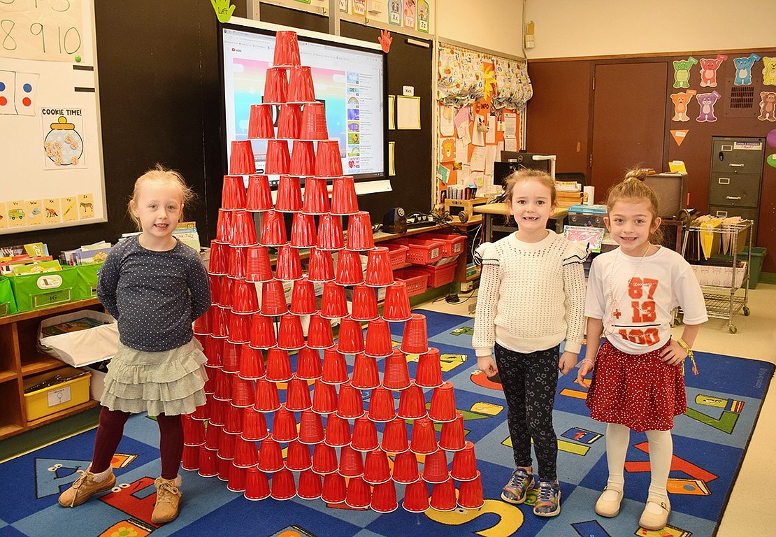 To celebrate their educational milestone, King Street School kindergarteners Isabella Hale (left), Mackenzie Toomb and Giada Lio build a tower by stacking 100 red cups in Lindsay Renda’s class.