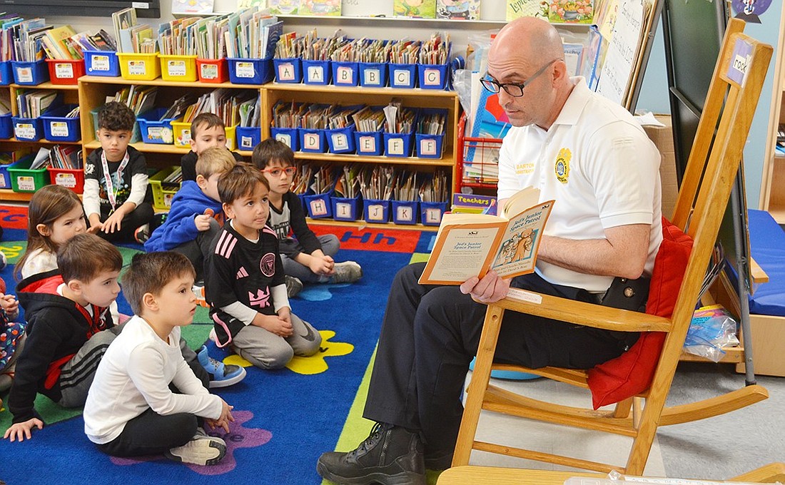 Port Chester-Rye-Rye Brook EMS Administrator Kenny Barton sits in the rocking chair of honor during his reading of “Jed’s Junior Space Patrol” in front of Karen Johnson’s class of kindergarteners on Friday, Mar. 8. He was one of the dozen guest readers invited to Ridge Street Elementary School as part of PARP Week, a PTA-sponsored event that aims to make reading fun for young students.