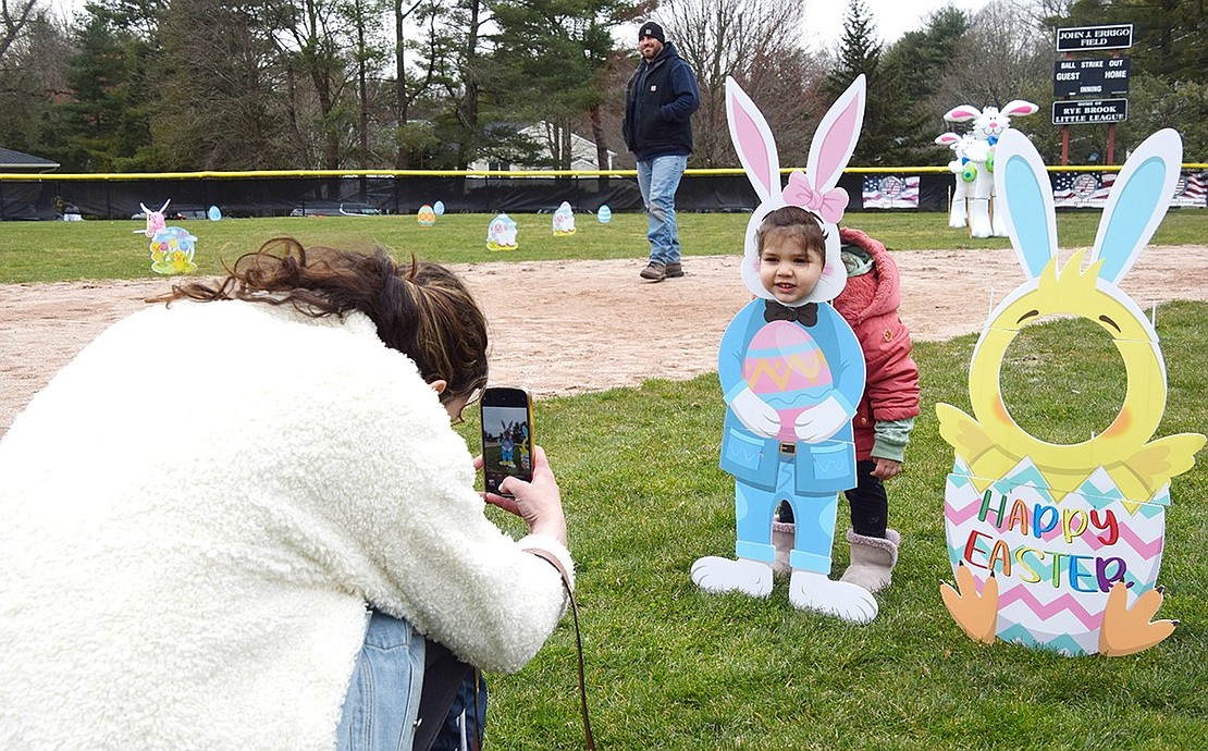 Berkley Drive resident Tamara Naudon snaps a photo of her 2-year-old daughter Sofia as she poses in one of the cardboard cutouts scattered around the field.