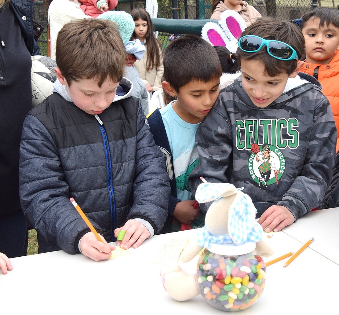Rye Brook residents Kiran Hirten (left), 7, and brothers Peter and Christopher Tevnan, 7 and 8 respectively, eagerly discuss how many jellybeans are in the jar. Whoever guessed the closest was awarded a stuffed animal.