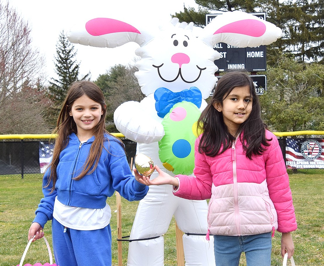 Ridge Street Elementary School second-graders Luciana Santorelli (left), 8, and Medha Madhu, 7, pose with a golden egg Santorelli found during the hunt in front of an inflatable Easter bunny.