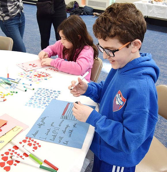 Ridge Street School third-grader Bennett Schinfeld decorates a card that will be sent to an Israel Defense Forces soldier overseas. In the background, second-grader Chloe Brous does the same.