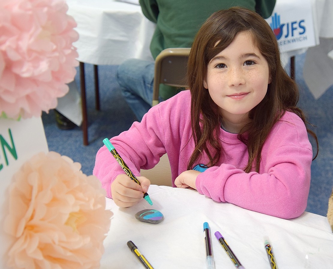 Spotting the camera, 8-year-old Lincoln Avenue resident Chloe Brous takes a moment away from decorating a kindness rock to smile.