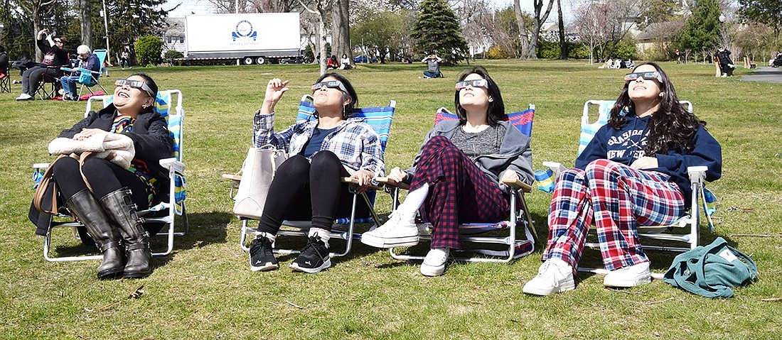 Port Chester residents Carmen Melgar (left), Sonia Napoli, Fiorella Napoli and Camila Napoli watch the solar eclipse on Monday, Apr. 8 from lawn chairs they brought with them to a viewing party organized by the Village of Port Chester at Lyon Park.