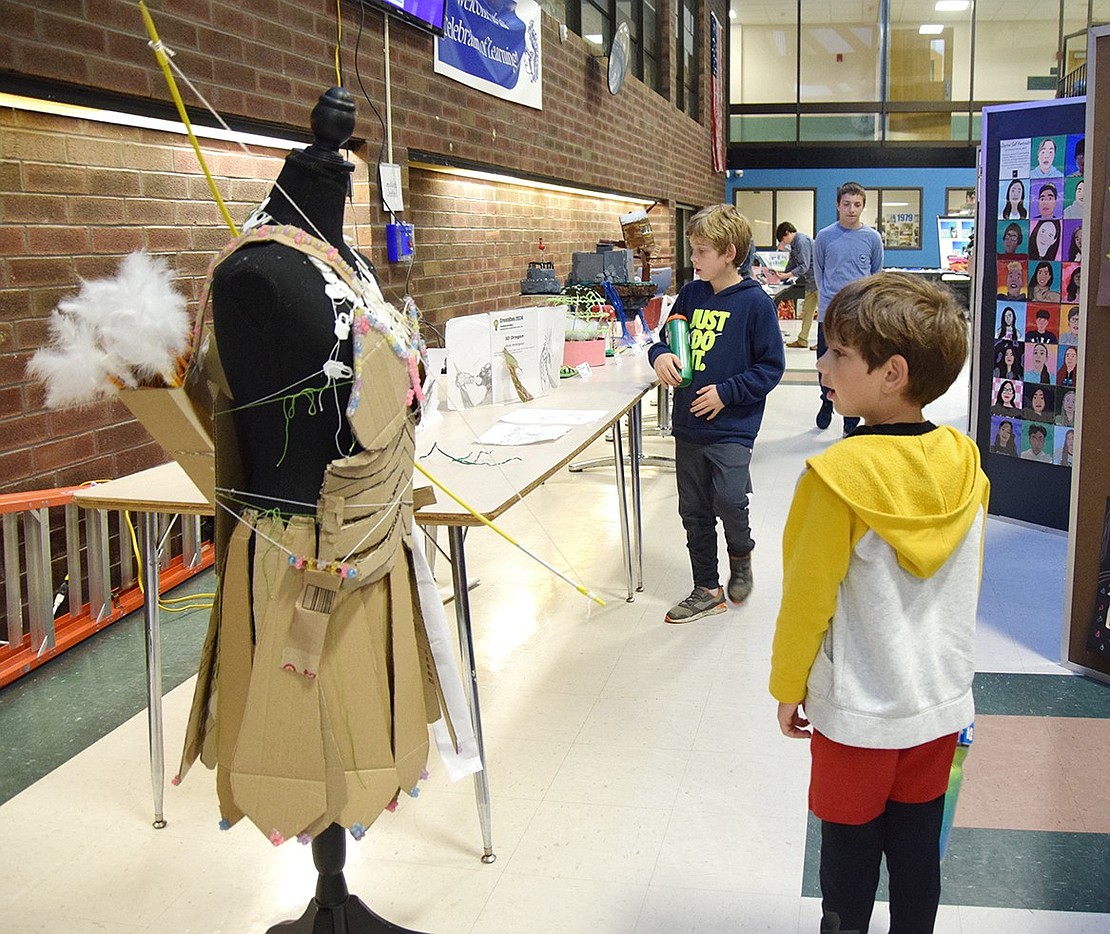 Zach Sternberg, a kindergartener at Ridge Street Elementary School, stops midstride to admire a “Very Reliable” suit of armor, a piece made of cardboard and other 3D printed parts by seventh-grader Samantha Geller.