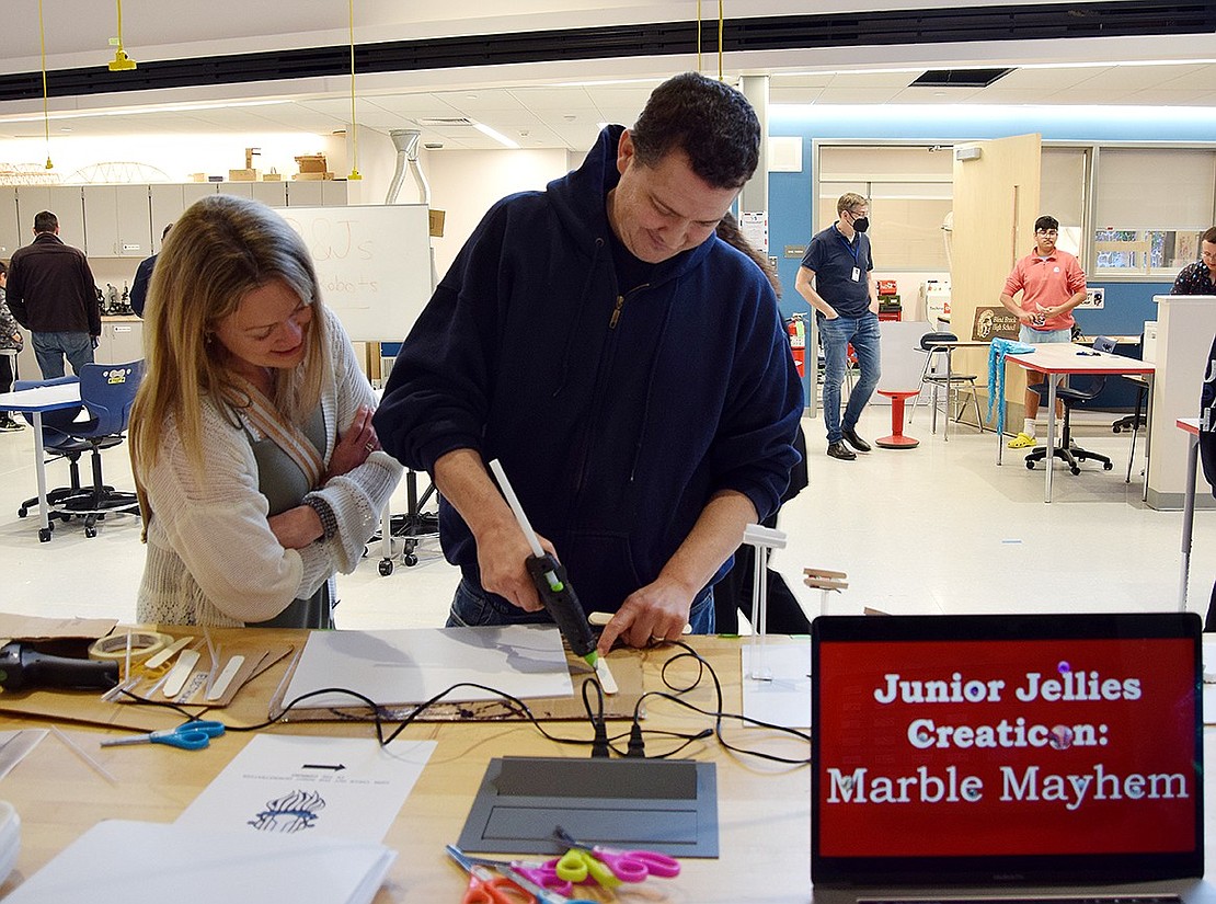 Meadowlark Road resident Perri Ross watches as her husband Jeff tries his hand at constructing a marble race, an activity presented by the Junior Jellies club from Ridge Street School.