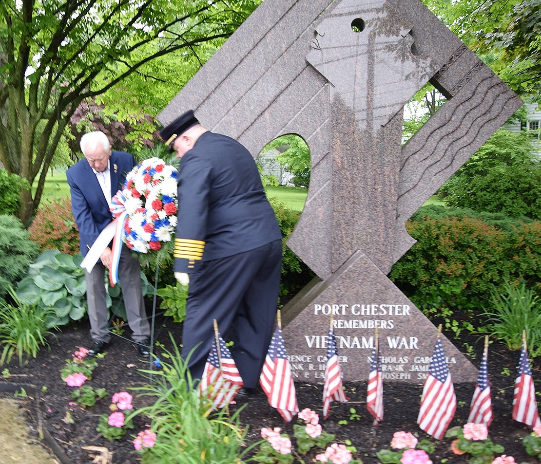 Retired Port Chester Police Lieutenant James Cahill and former Port Chester Fire Chief Michael DeVittorio place a memorial wreath at the Vietnam War memorial at the corner of King Street and Putnam Avenue.