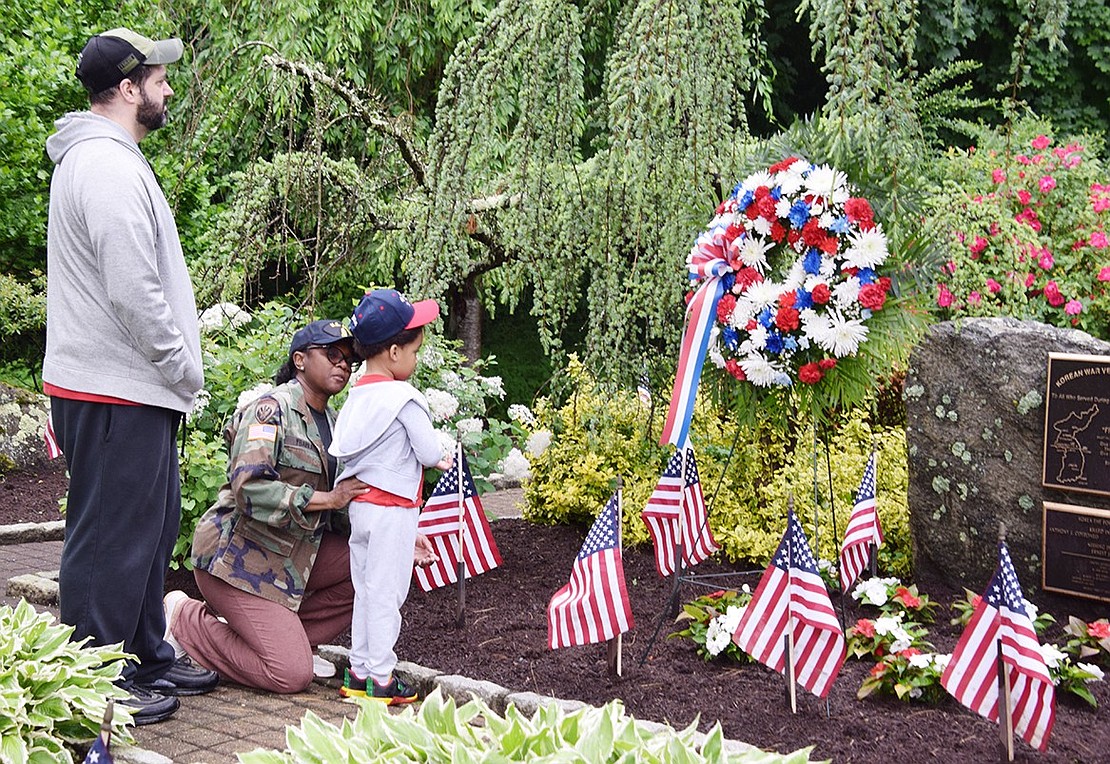 U.S. Army veteran Carleen Ybarra, accompanied by her husband David, teaches their 5-year-old son David about the Korean War at the memorial dedicated to the local service members who died in that conflict at the entrance to Crawford Park on Memorial Day, Monday, May 27. The Ybarras are Rye Brook residents.