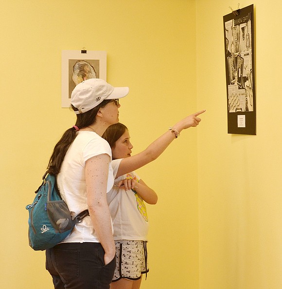 Sarah Craighead, 10, and her mom, Danielle, of Sleepy Hollow Road, Rye Brook, study a collage called “The Worried” created by Tara O’Reilly, a student at Rye Neck High School, in an upstairs room at Crawford Mansion Community Center where artwork of students from Port Chester, Blind Brook and Rye Neck schools was displayed.