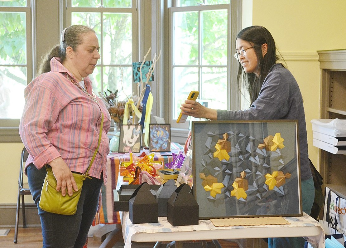 Ann Ribuffo of Maple Place looks at math art created by Shiying Dong of Greenwich at Crawford Mansion Community Center. The artist, who said “Everything I do is math inspired, but I try to make it pretty,” shows Ribuffo additional pieces she has made on her cell phone.