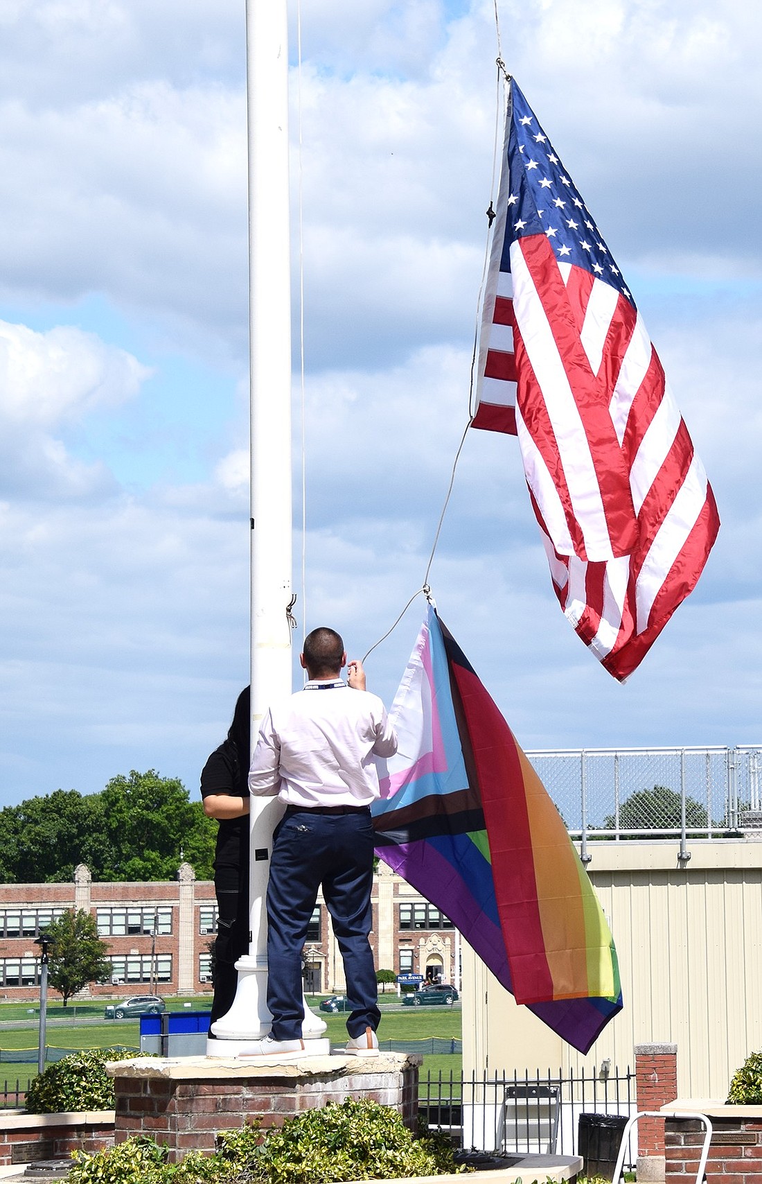 Port Chester High School Principal Luke Sotherden works in tandem with a member of the Gay-Straight Alliance to raise the Pride flag in front of the building on Thursday, May 30, to commemorate the start of Pride Month, recognized throughout June.