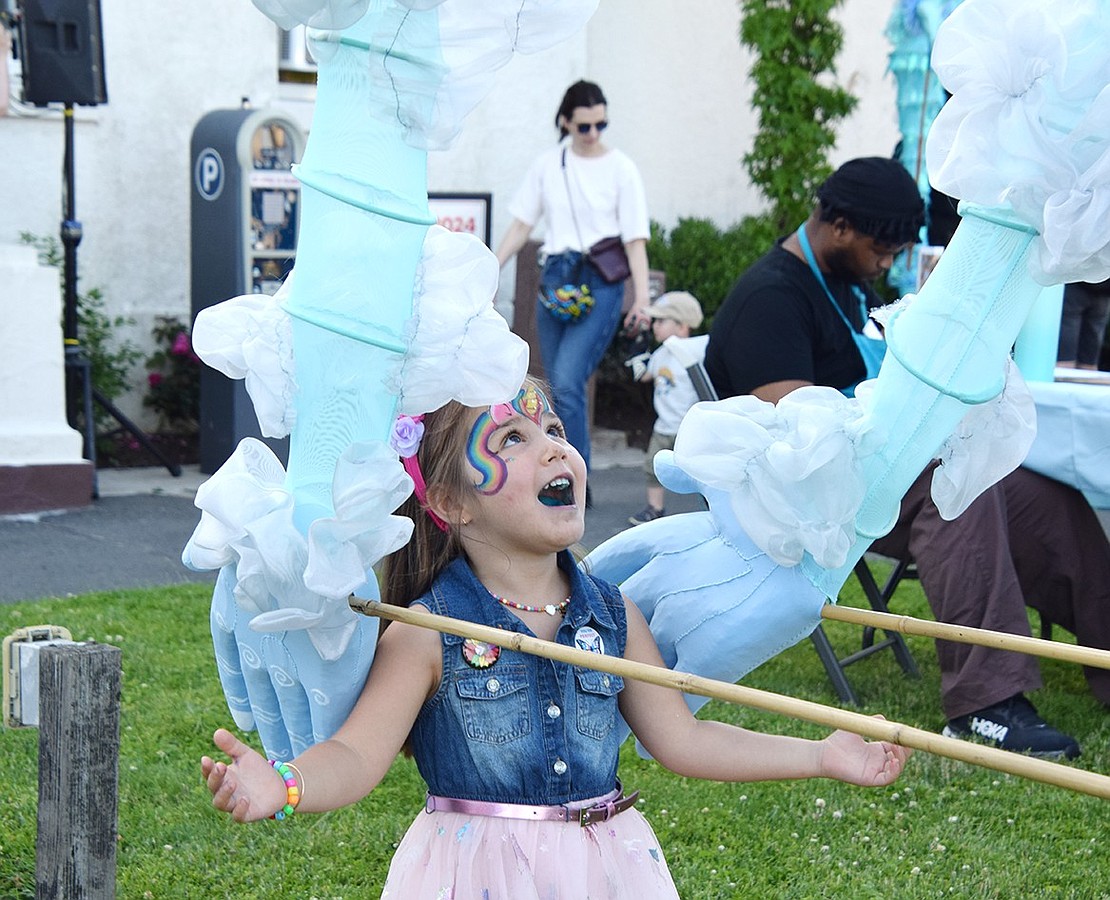 Four-year-old Rye resident Sloane Foster looks up in awe as the arms of a giant puppet reach around her.