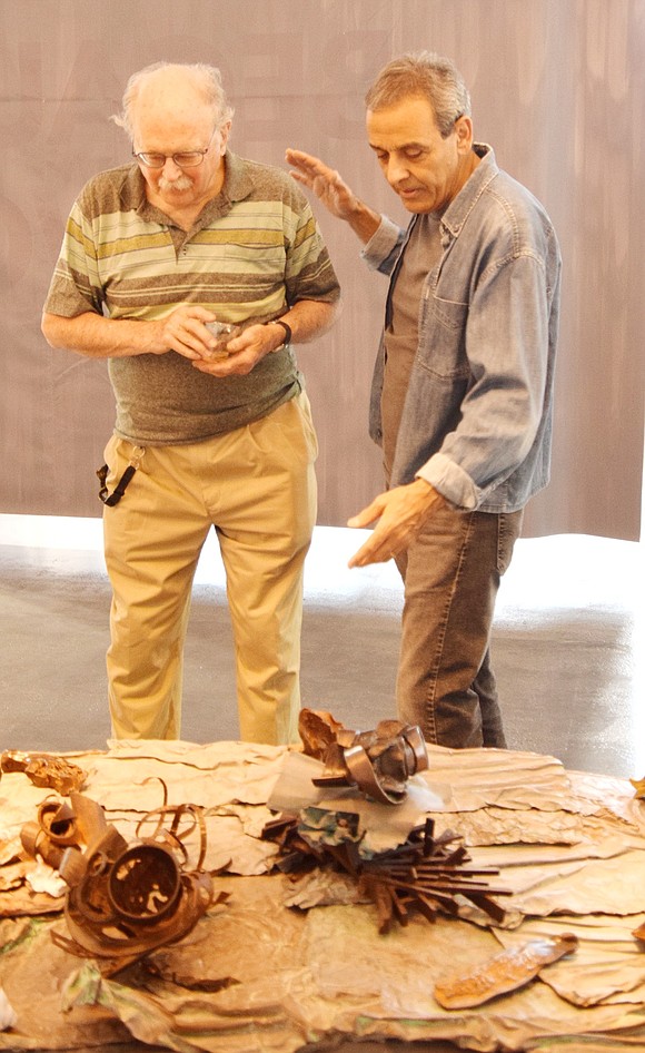 Yonkers resident David Daykin (left) listens intently as Serdar Arat, a Turkish artist who lives on Hobart Avenue, describes how he combined fiberglass, wood and other materials to create his piece ‘Departing Skies and Fallen’ at the Neptune in June exhibit at 33 New Broad St.