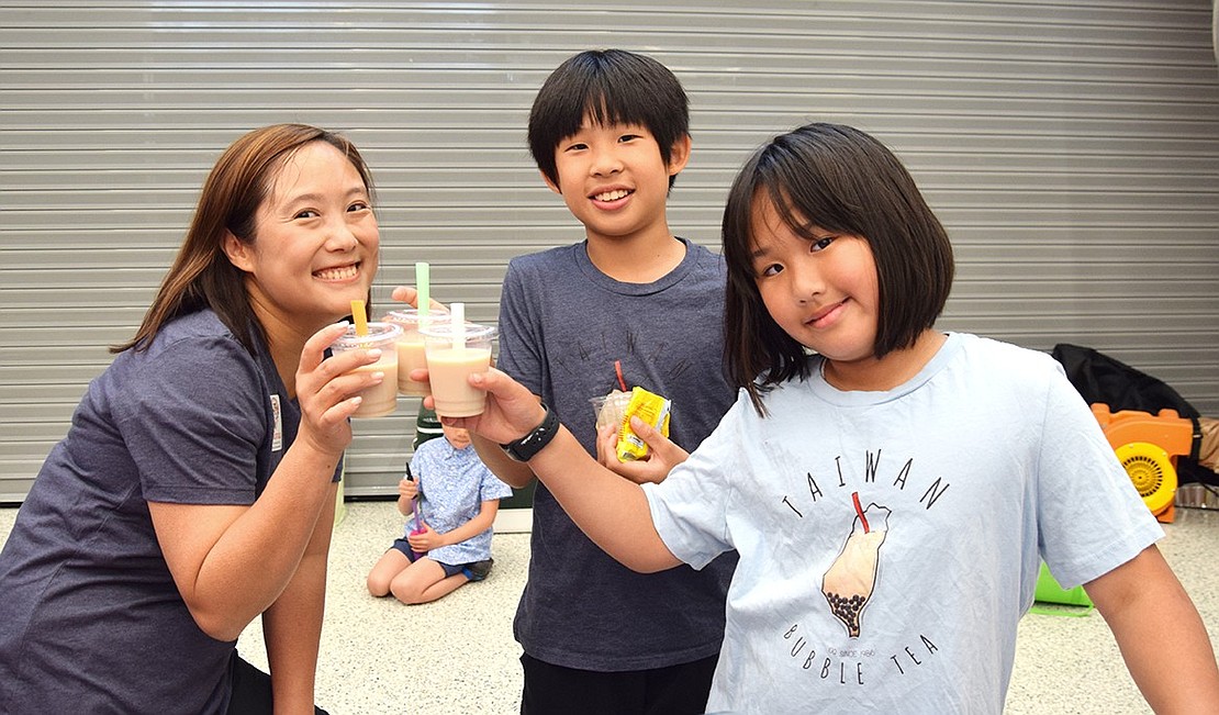 Pamela Huang (left), fourth-grader Sidney Wang and fifth-grader Madison Wong toast with their cups of Taiwanese milk tea. Huang, one of the organizers of the event, hopes to hold a Multicultural Festival every year.