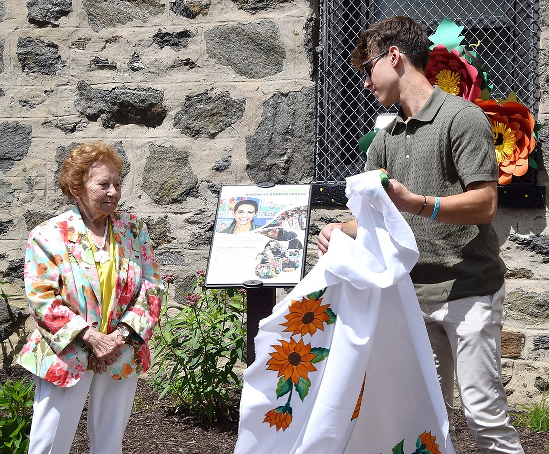 As mother and son of the honoree, Ela Navarro (left) and Cody Jones unveil the memorial plaque for the Clara Jones Kindness Garden at Thomas Edison Elementary School on Monday, June 10. The beloved kindergarten teacher died of cancer in September 2022.