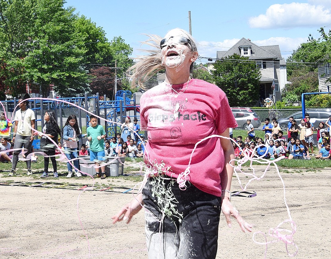 As Assistant Principal Jennifer Mundo attempts to perform jumping jacks, a group of students sprays her with silly string.